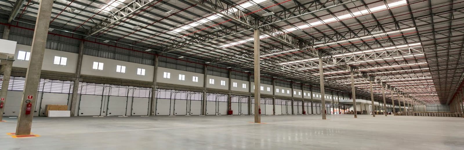 Interior de galpão logístico com pé-direito alto, piso nivelado e linha de docas
