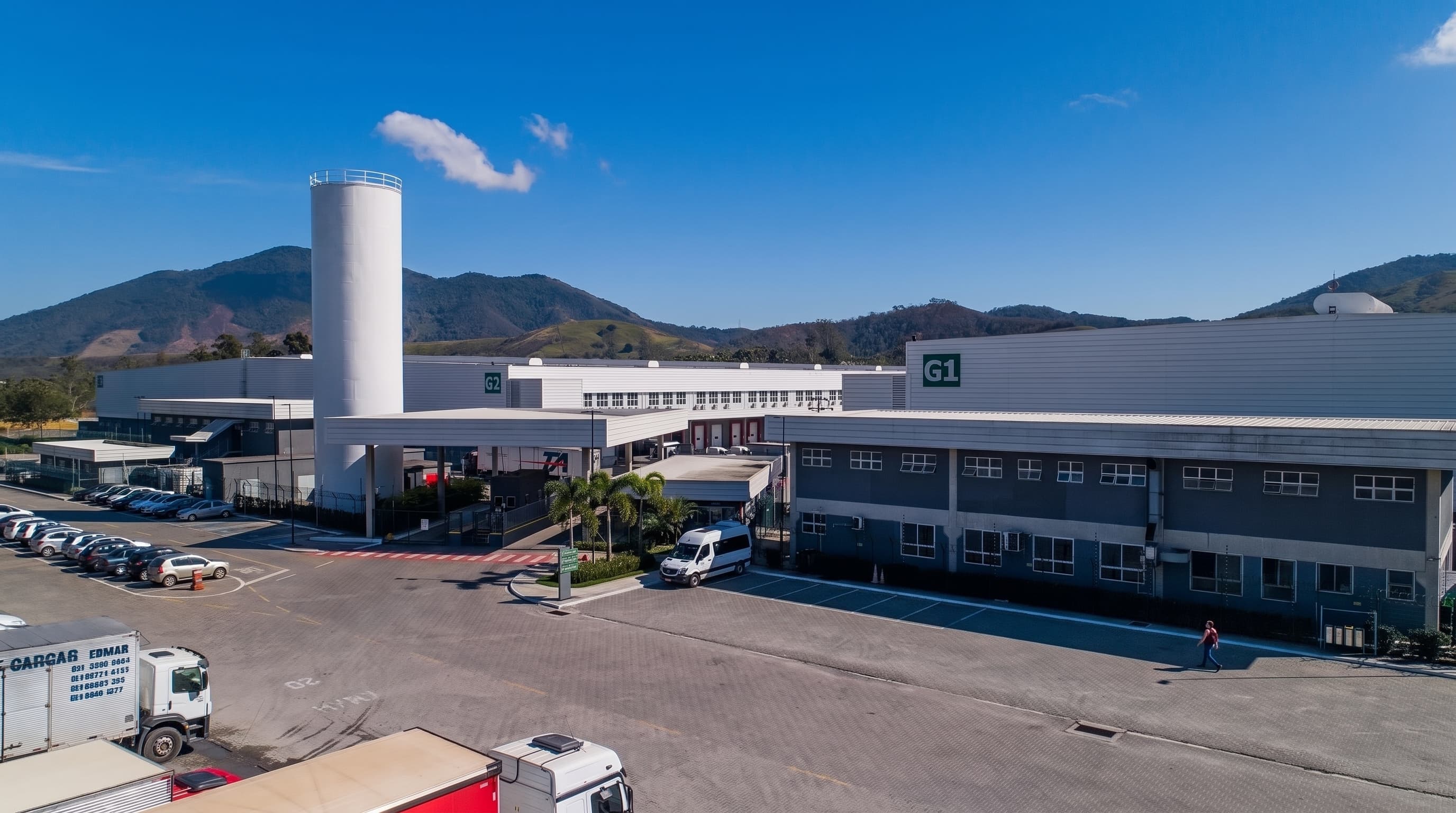 Portaria e acesso de caminhões a condomínio logístico com serra ao fundo